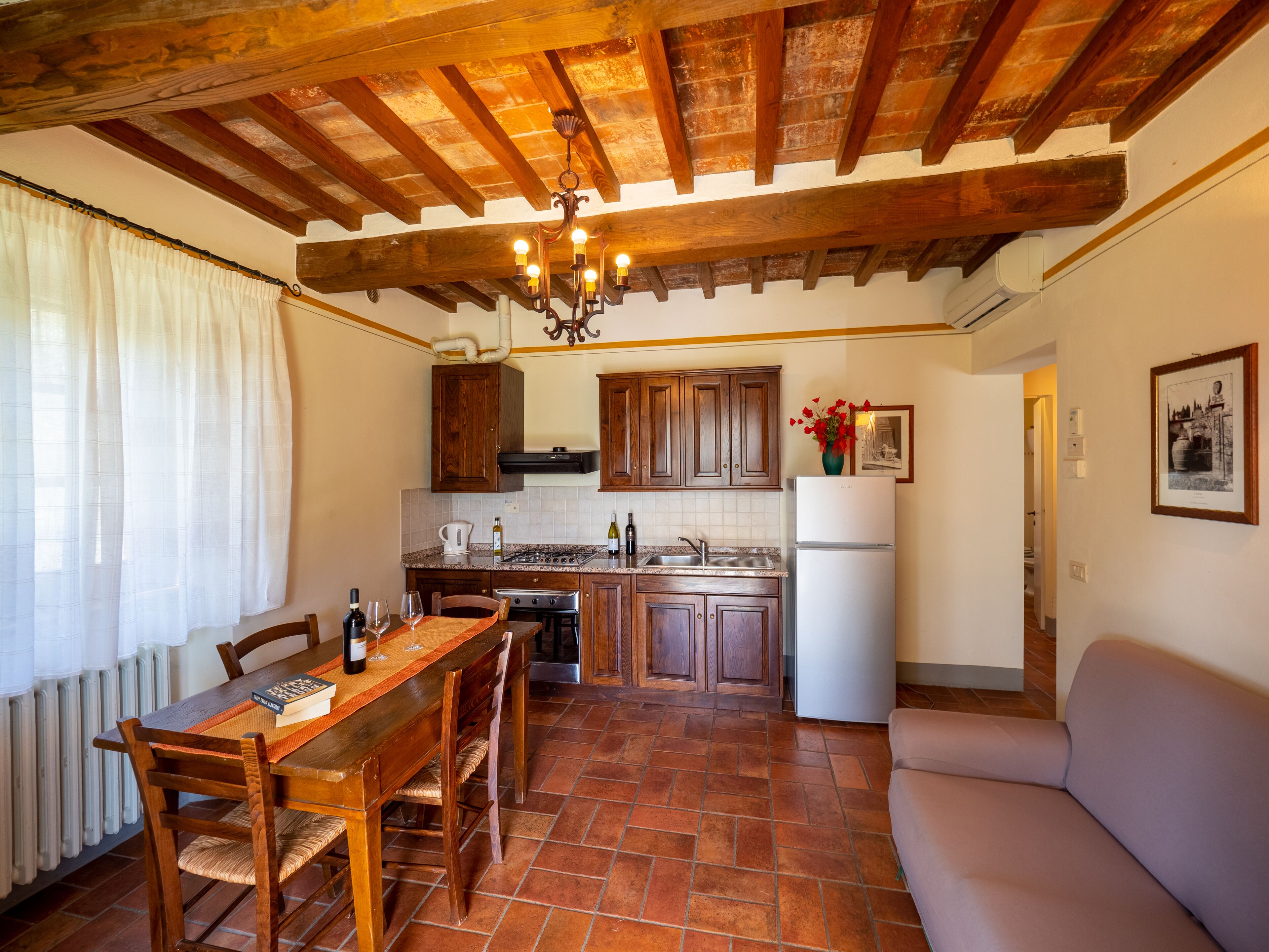 A kitchen with wooden cabinets, a dining table with chairs, a built-in oven, and a refrigerator.