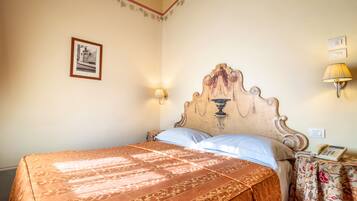 A room with a bed, a framed picture on the wall, a lamp, and a telephone on a side table.