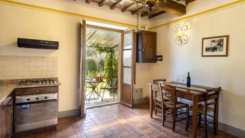 A kitchen with a gas stove, oven, and a dining area with a table and chairs.