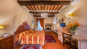 Una habitación tradicional con cama, escritorio, chimenea y candelabro.