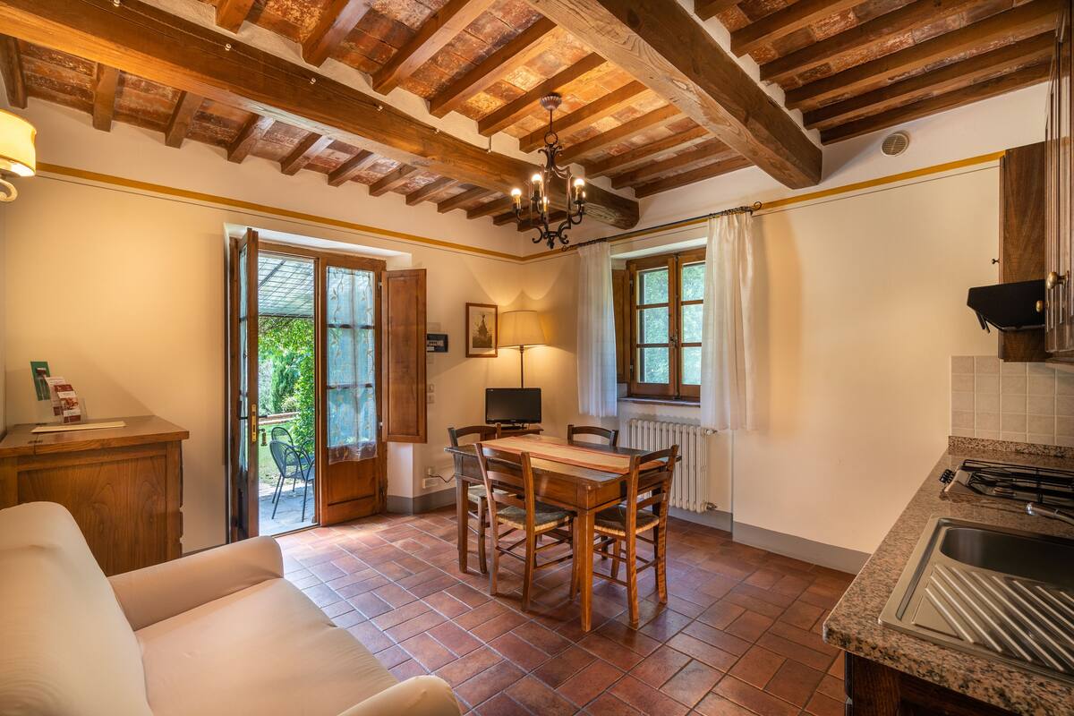 Une cuisine chaleureuse avec une table et des chaises en bois, un four encastré et une fenêtre avec des rideaux.