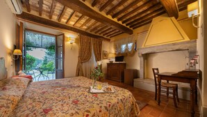 Un dormitorio con cama, una mesa de comedor y televisor. Tiene un balcón con vistas a la vegetación.