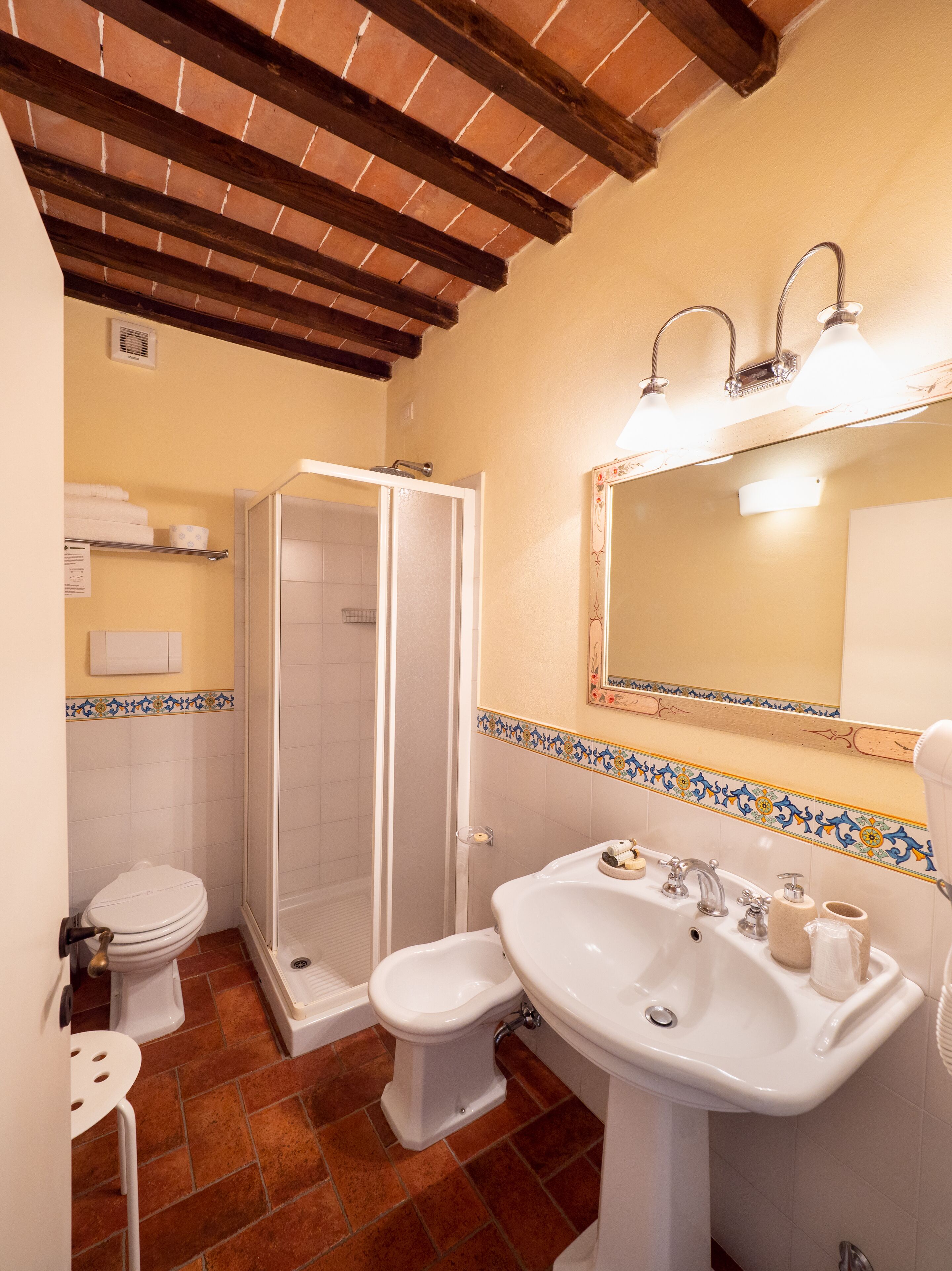 A bathroom with a shower, toilet, bidet, and sink.