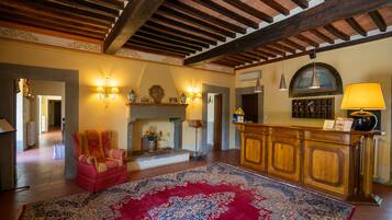 A spacious living room with a fireplace, a red patterned rug, and a wooden cabinet with a lamp.