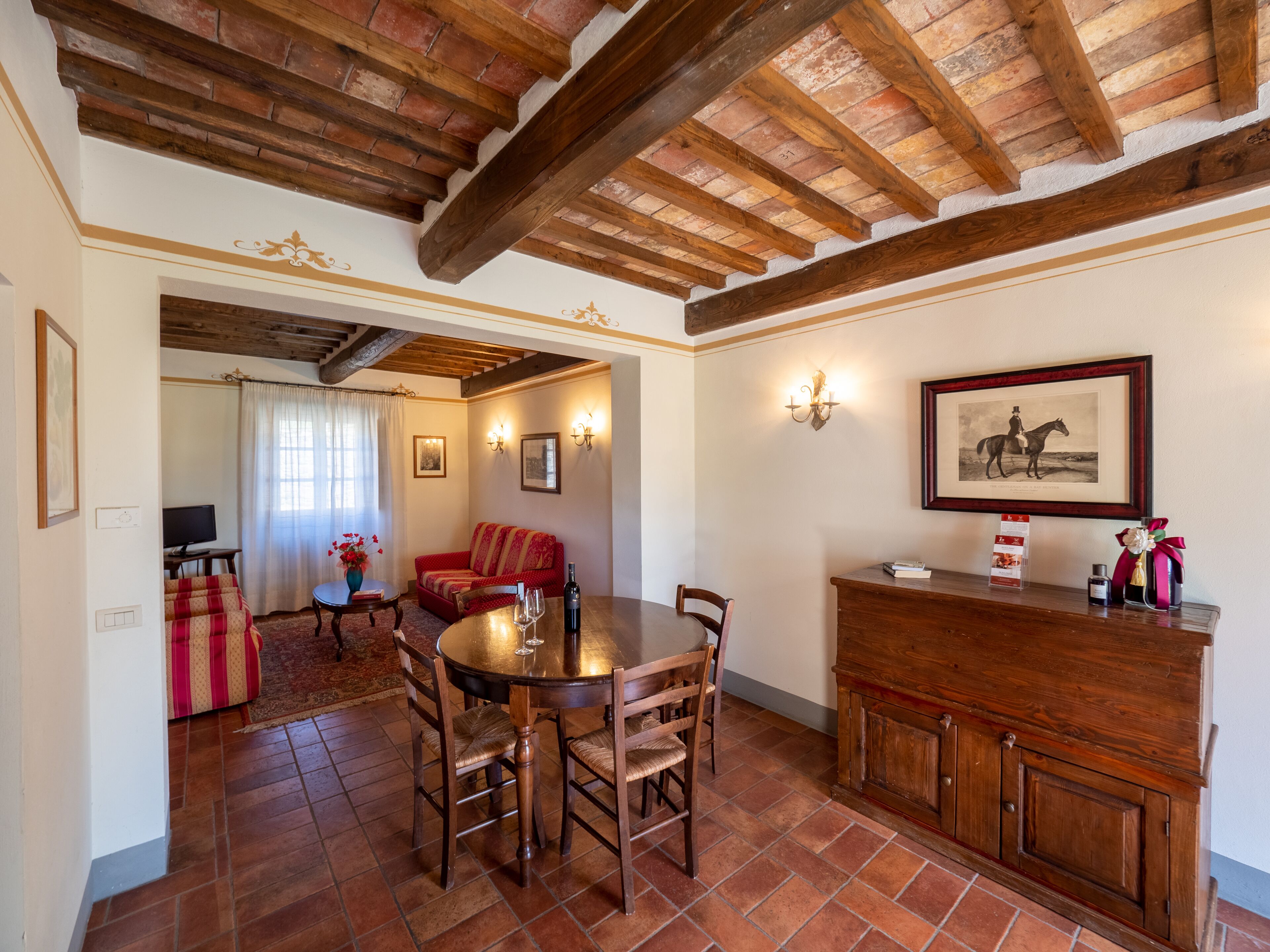 A dining area with a wooden table and chairs, a sofa, and a fireplace.