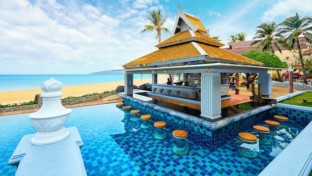 Ein Poolbereich mit Bar und Sitzgelegenheiten mit Blick auf einen Strand.