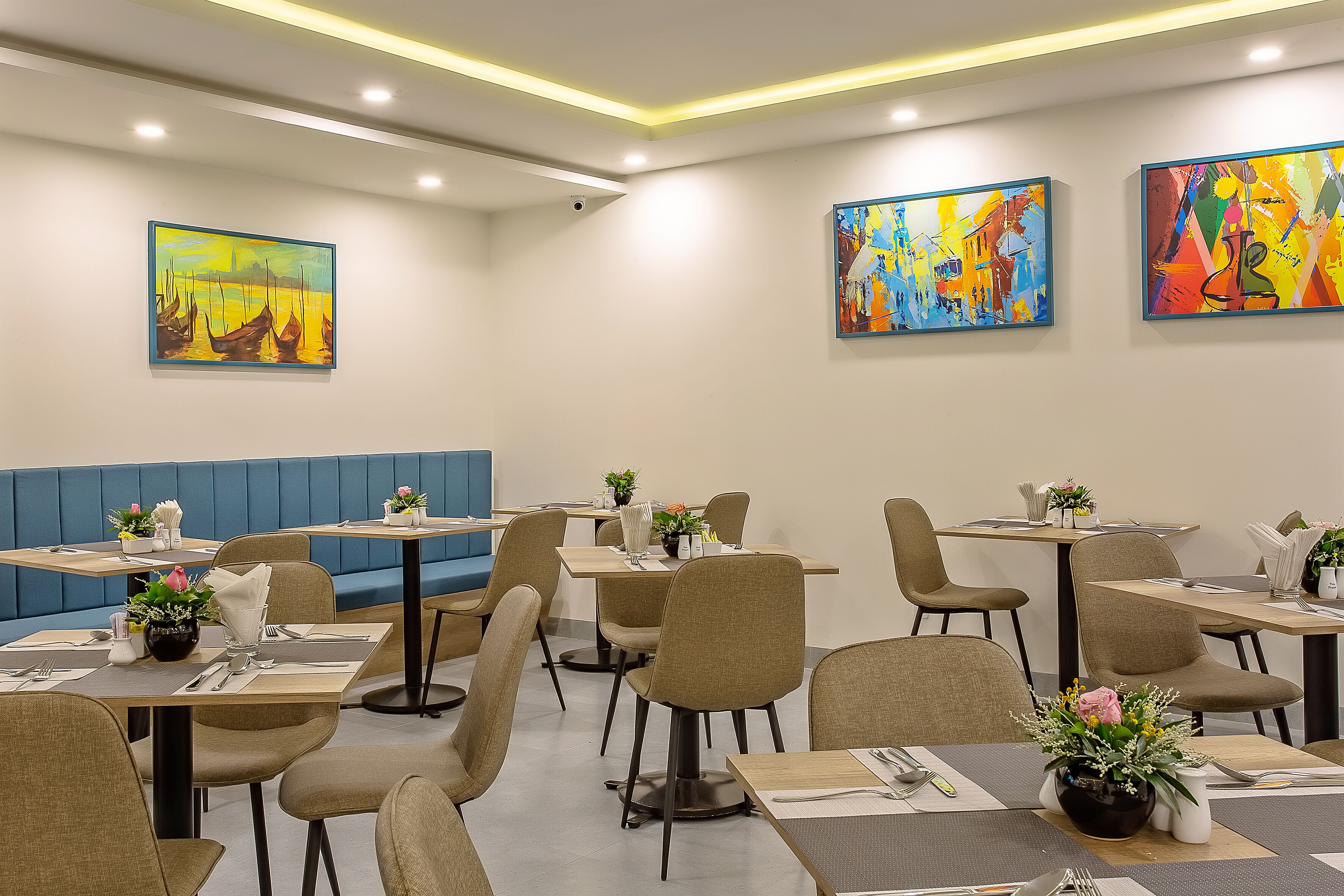 A dining area with tables, chairs, and artwork on the walls.