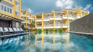A swimming pool with lounge chairs and a building with balconies. - Aurora Riverside Hotel and Spa (Da Nang)