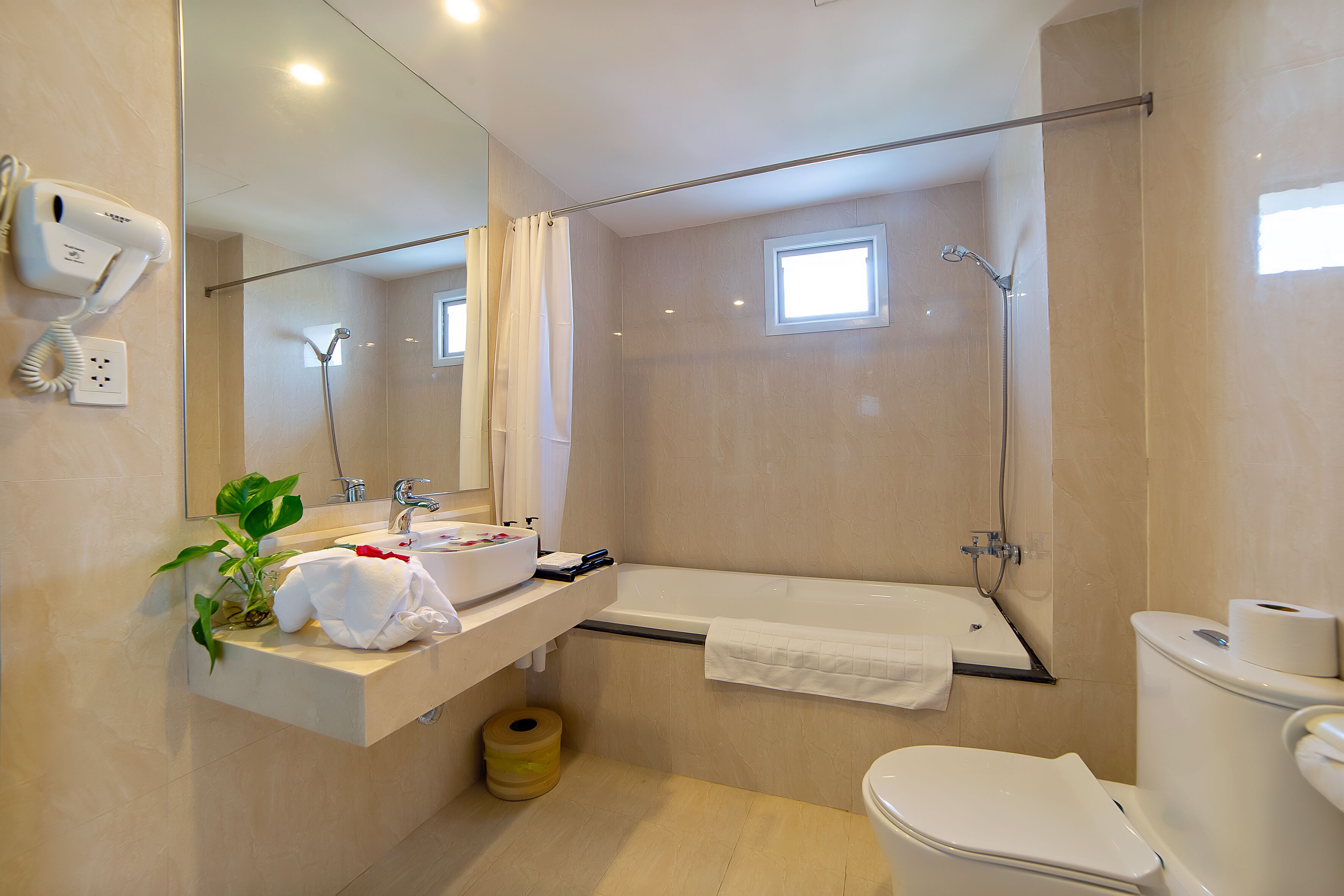 Un baño moderno con bañera, inodoro y lavamanos con espejo.