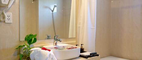 Een badkamer met een wastafel, spiegel, douche en een haardroger aan de muur.