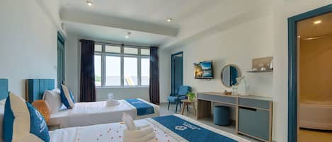 A hotel room with two beds, a desk, a chair, a small table, a mirror, and a bathroom.