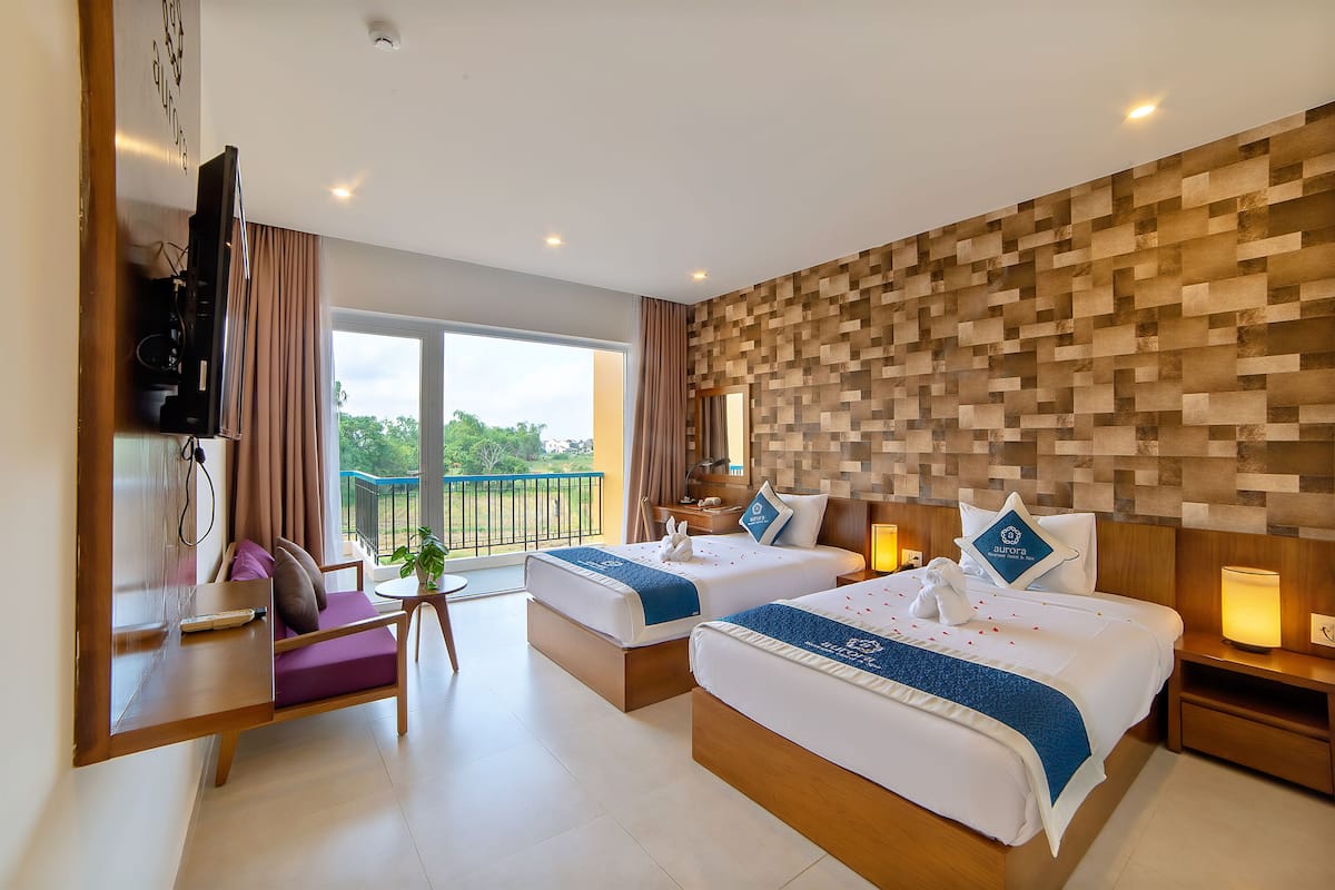 Quarto de hotel com duas camas, televisão, escrivaninha e varanda com vista.