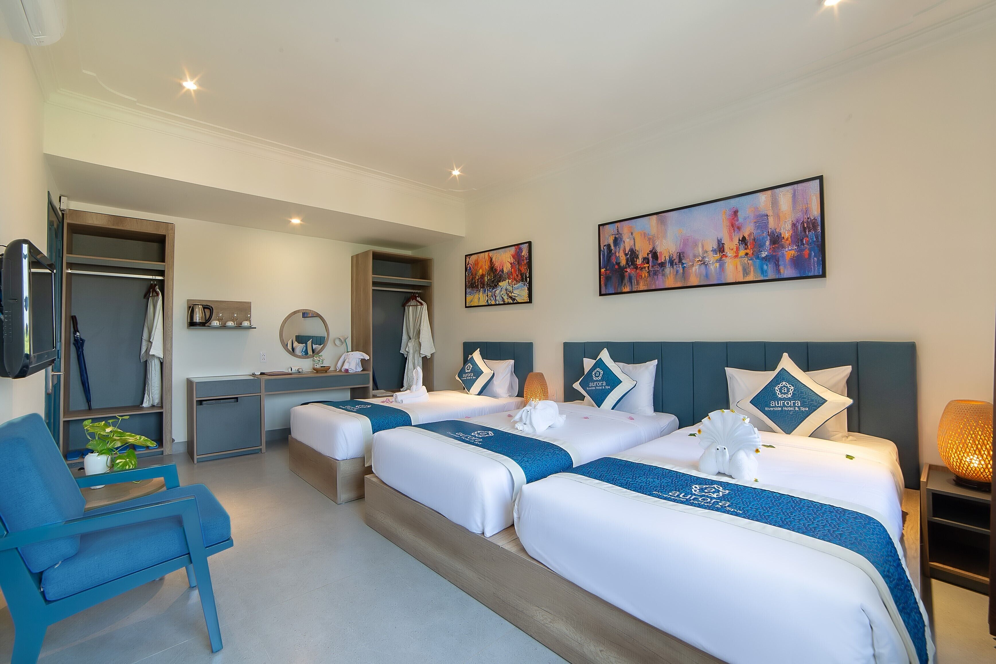 Habitaci ón de hotel con dos camas, un escritorio, una silla, un televisor y obras de arte en las paredes.
