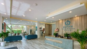 A hotel reception area with a modern design, featuring a reception desk, seating area, and potted plants. - Aurora Riverside Hotel and Spa (Da Nang)