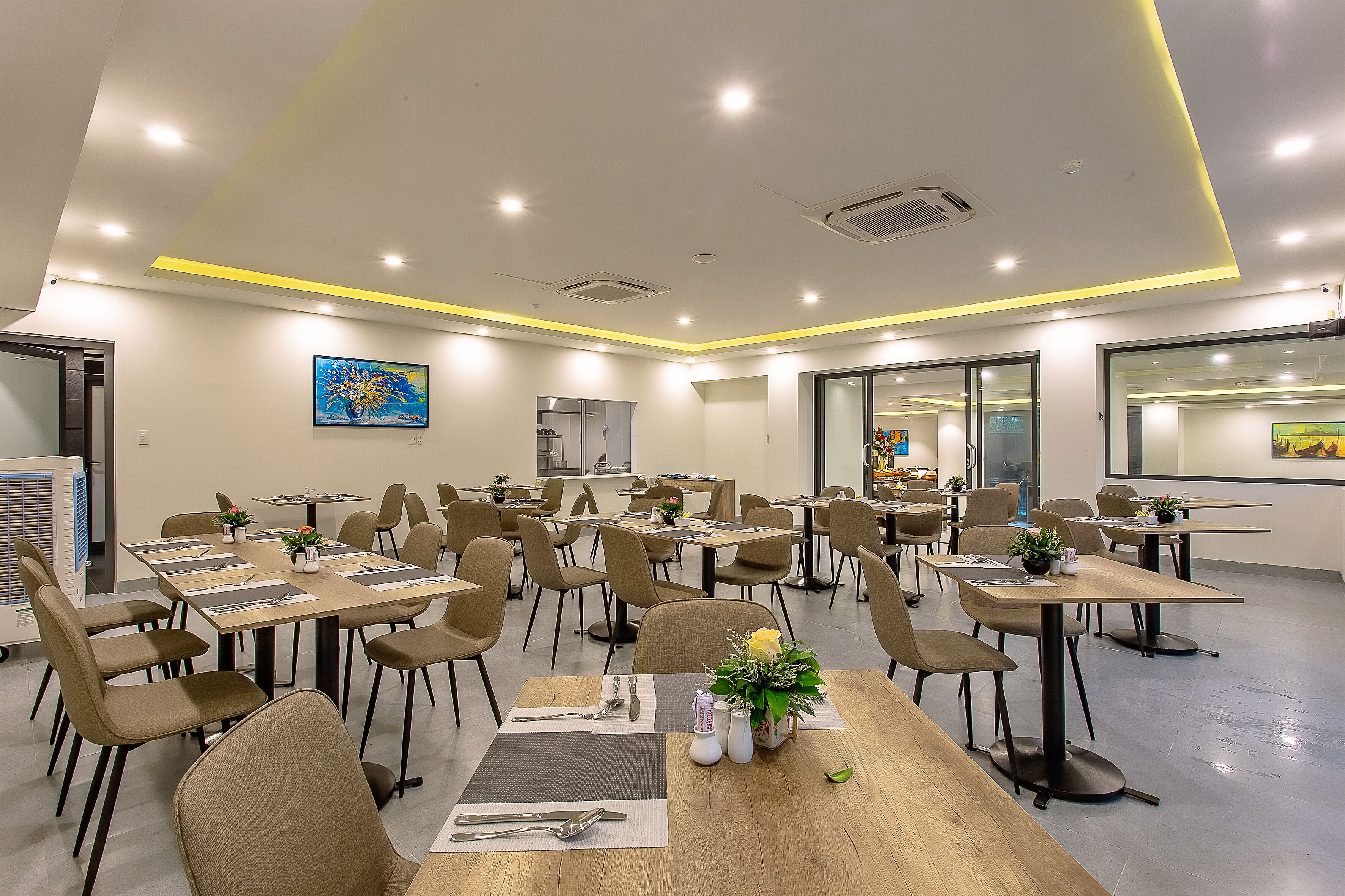 A modern dining area with multiple tables and chairs, equipped with place settings and centerpieces.
