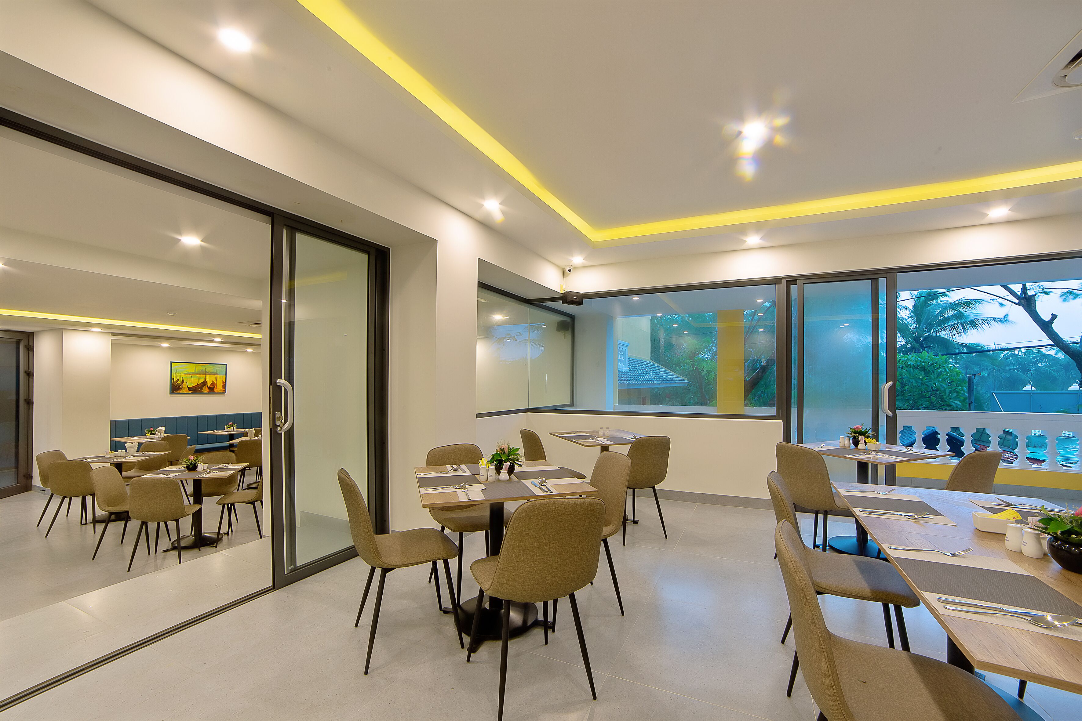 Un comedor moderno con divisiones de vidrio, varias mesas y sillas.