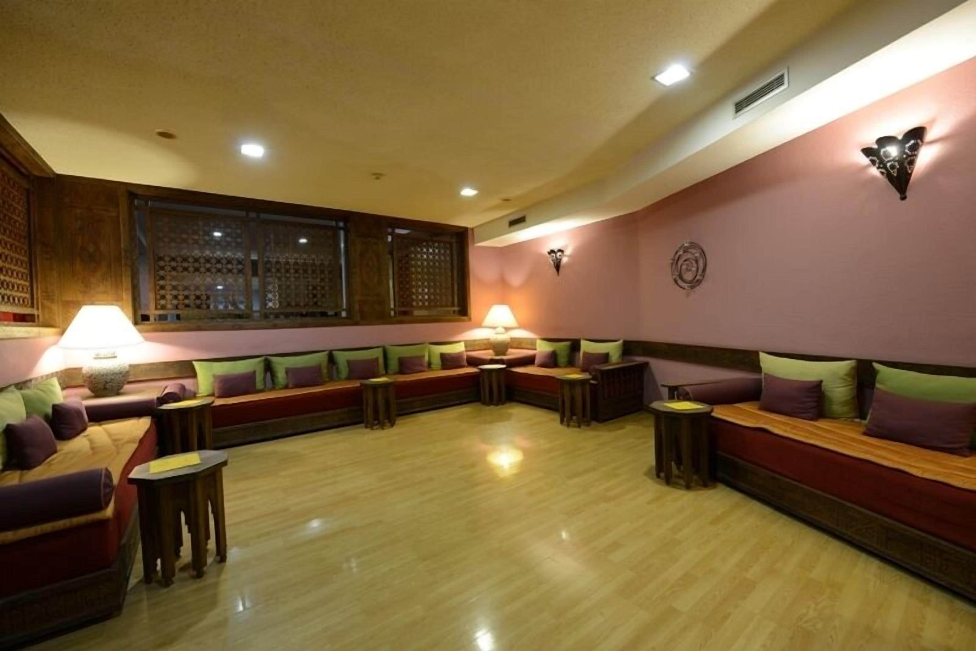 A room with a wooden floor, a sofa set, and two lamps.