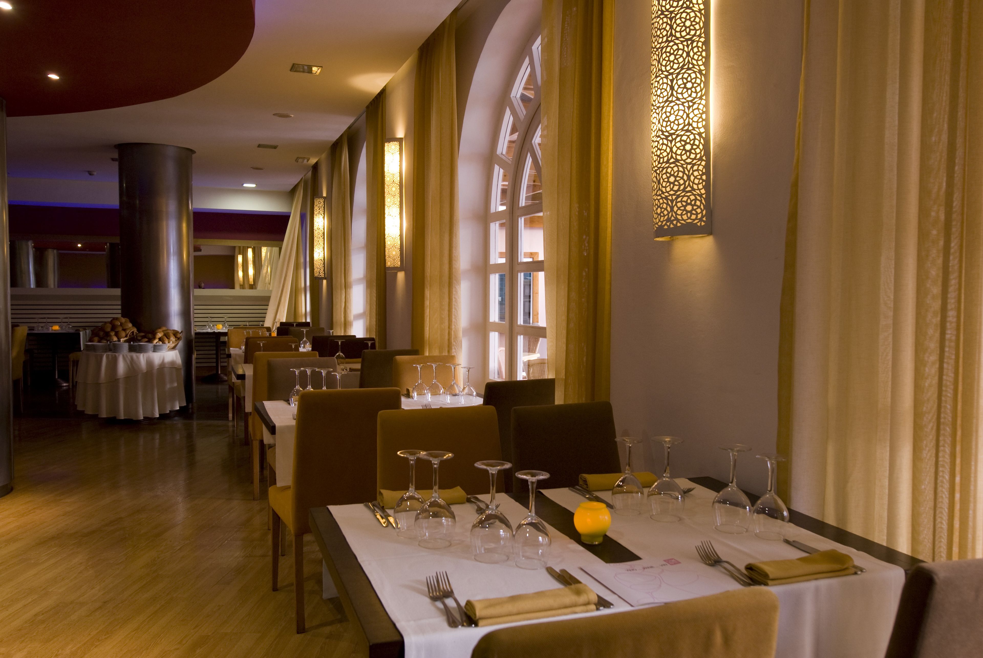 A restaurant with tables set for dining, featuring a warm ambiance with soft lighting and elegant decor.