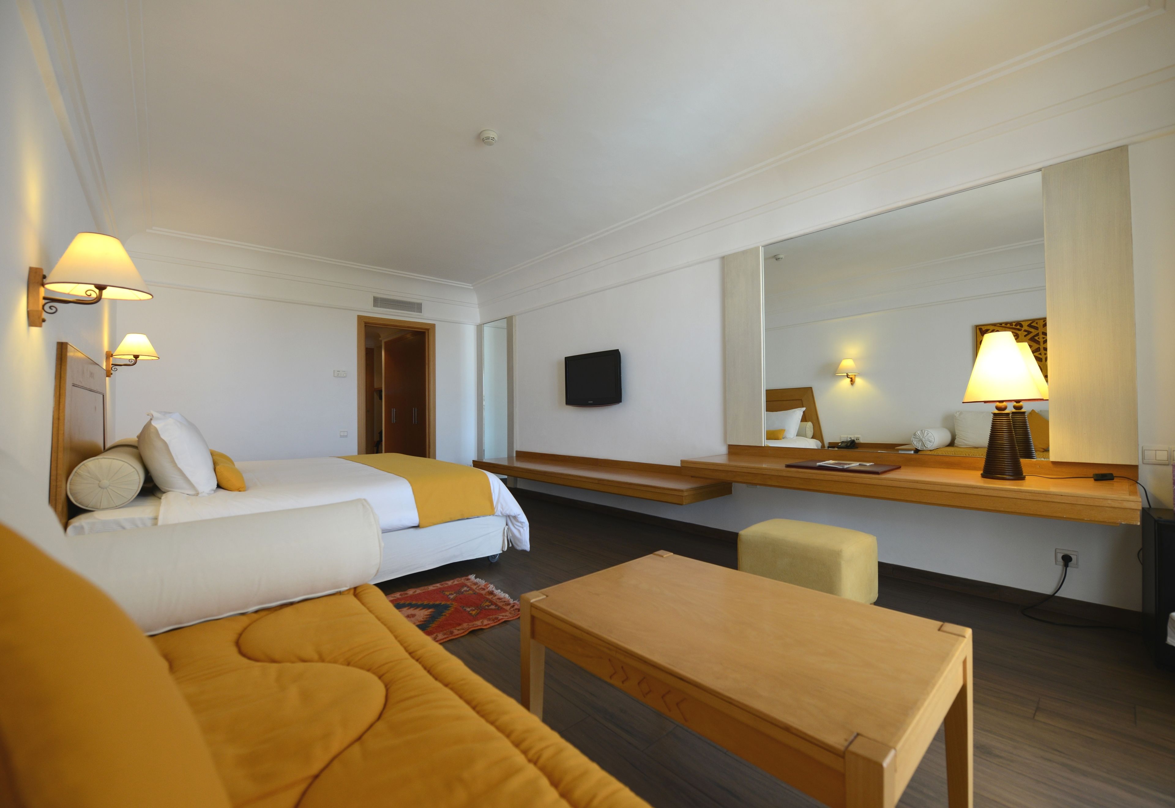 Una habitación de hotel con cama, sofá, escritorio, silla y televisor.