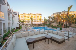 Una piscina al aire libre, sombrillas, sillones reclinables de piscina