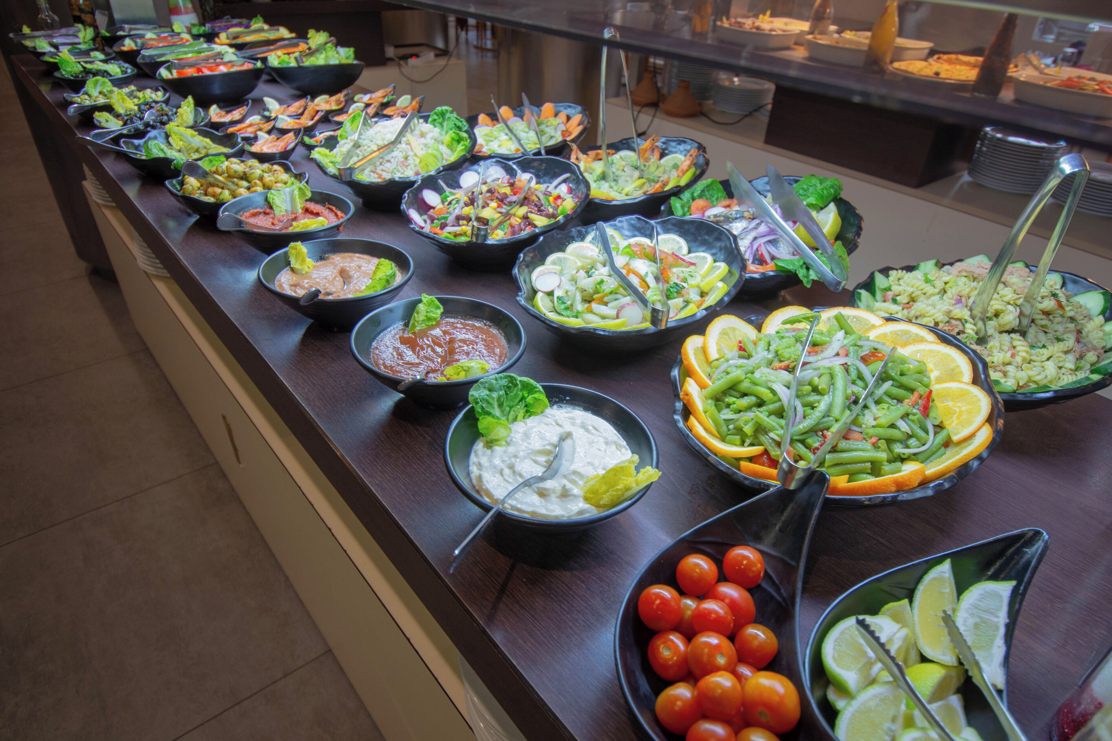 Un buffet proposant une variété de plats, notamment des salades, des légumes et des sauces.