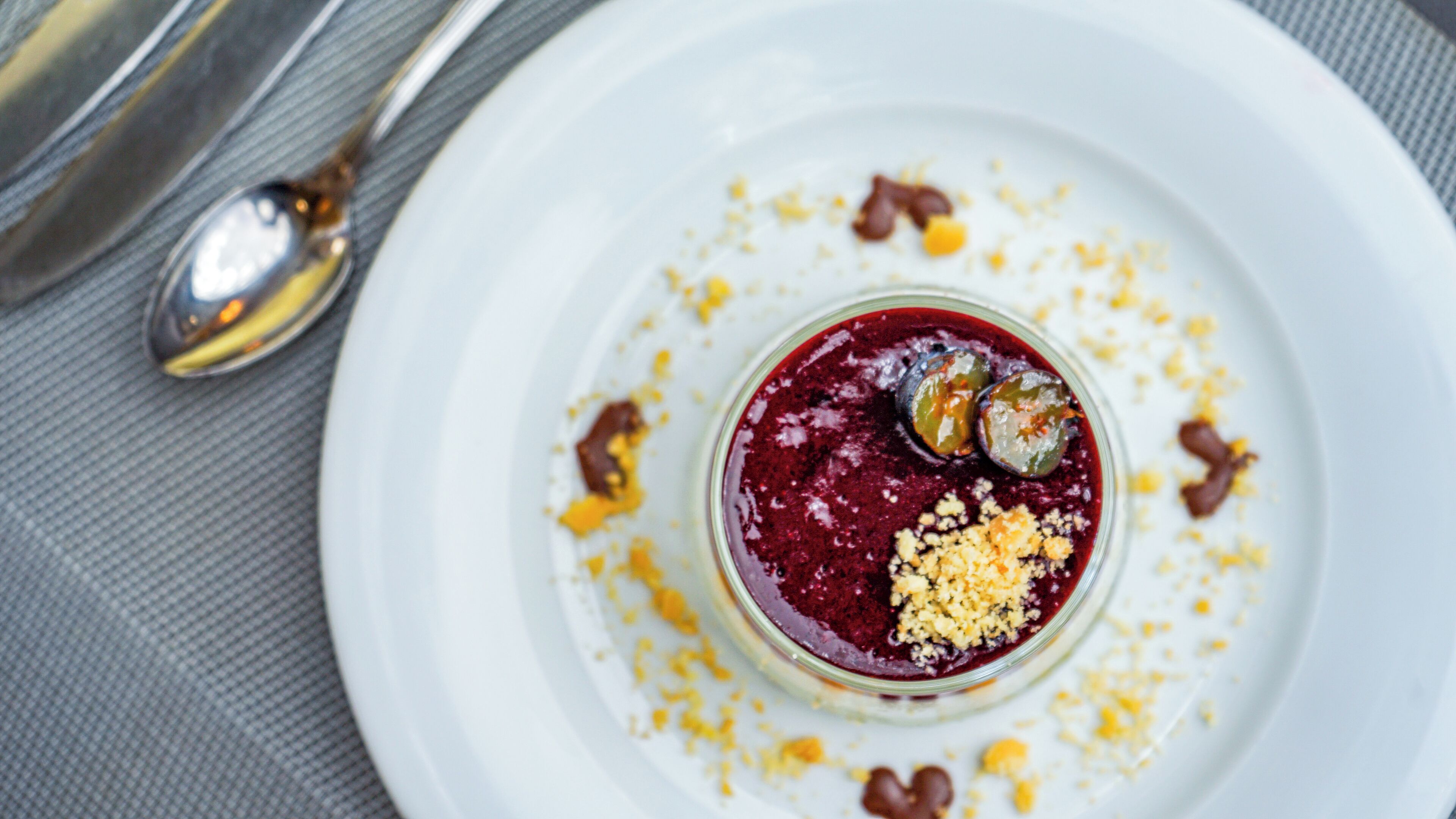 A dessert on a white plate with a spoon and a fork beside it.