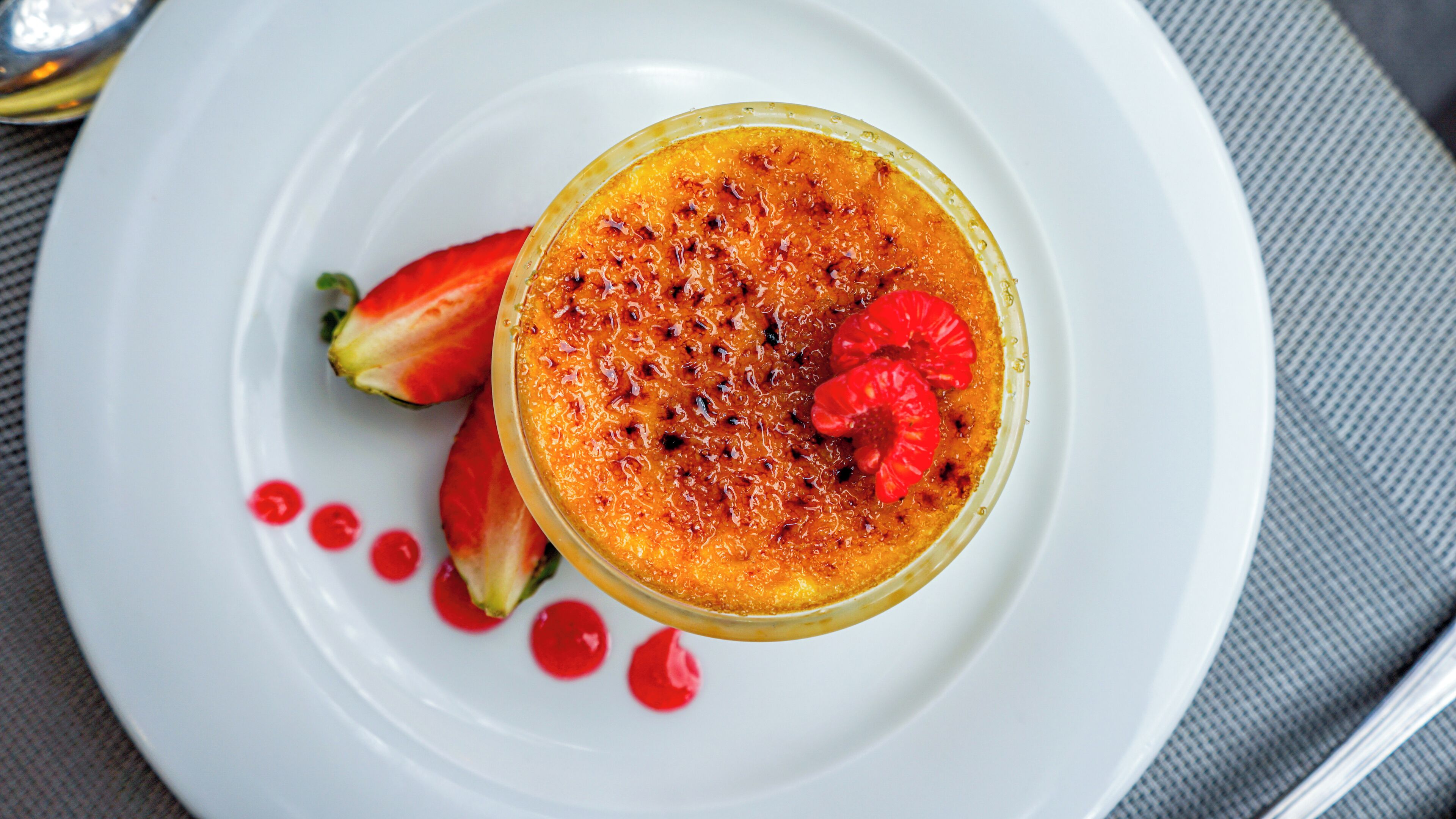 A dessert on a white plate with strawberries and red sauce.