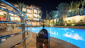A swimming pool with a decorative lantern in the center, surrounded by a metal railing and palm trees. - Timoulay Hotel & Spa Agadir (Agadir)