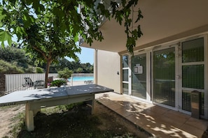 A patio with a table, a pool, and a house with sliding glass doors. - Comfort Aparthotel Six-Fours (Six-Fours-les-Plages)