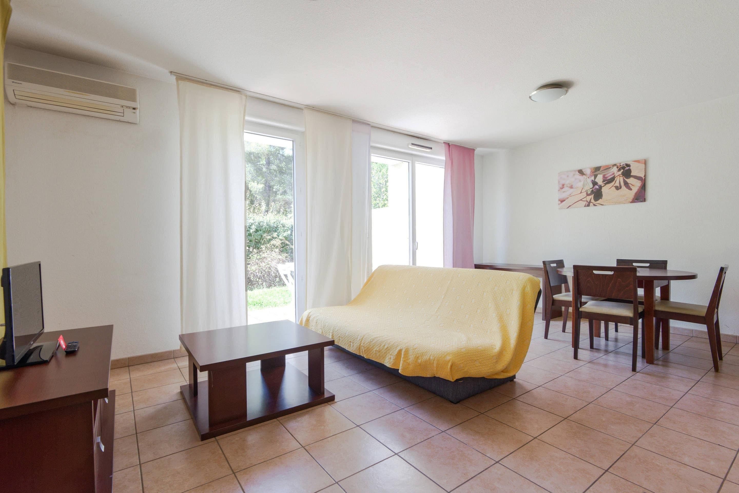 A room with a bed, a desk, a chair, a table, and a window.