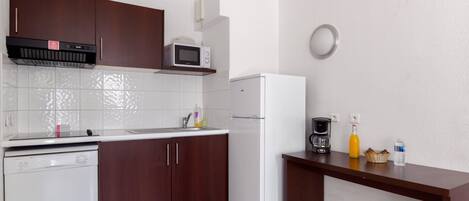 A compact kitchen with a dishwasher, microwave, refrigerator, and a coffee maker on the counter.