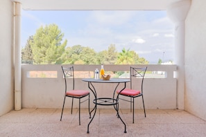 Ein Balkon mit zwei Stühlen, einem Tisch, einer Wasserflasche und einem Korb.