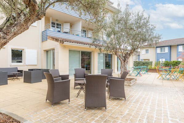 A patio area with wicker furniture and a view of a building with balconies.