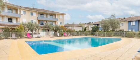 Una piscina al aire libre de temporada, sombrillas
