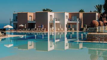A hotel with a swimming pool, sun loungers, and a view of the sea.