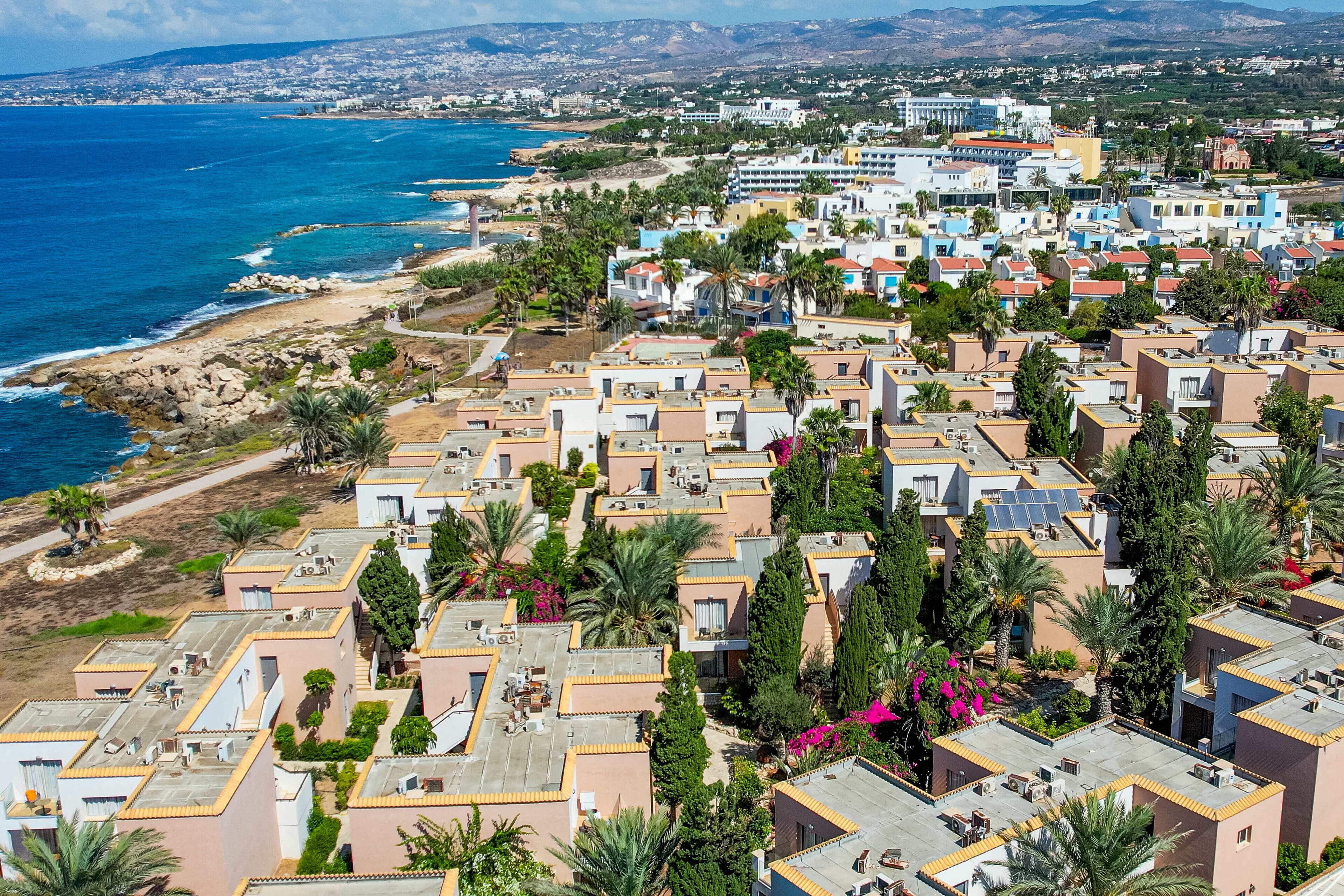 Zona residencial costera con edificios modernos, una playa y palmeras.