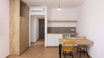 Una cocina compacta con una mesa y sillas de madera, una lámpara colgante y un horno empotrado.