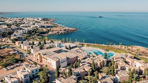 Un complejo turístico frente al mar con piscina, villas en la playa y vistas al océano.