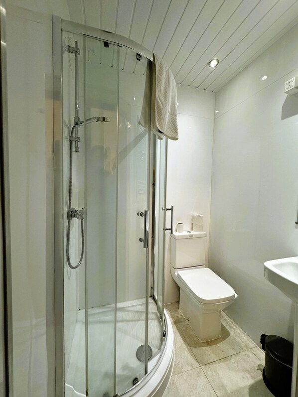 Un baño moderno con cabina de ducha de vidrio, inodoro y lavamanos.