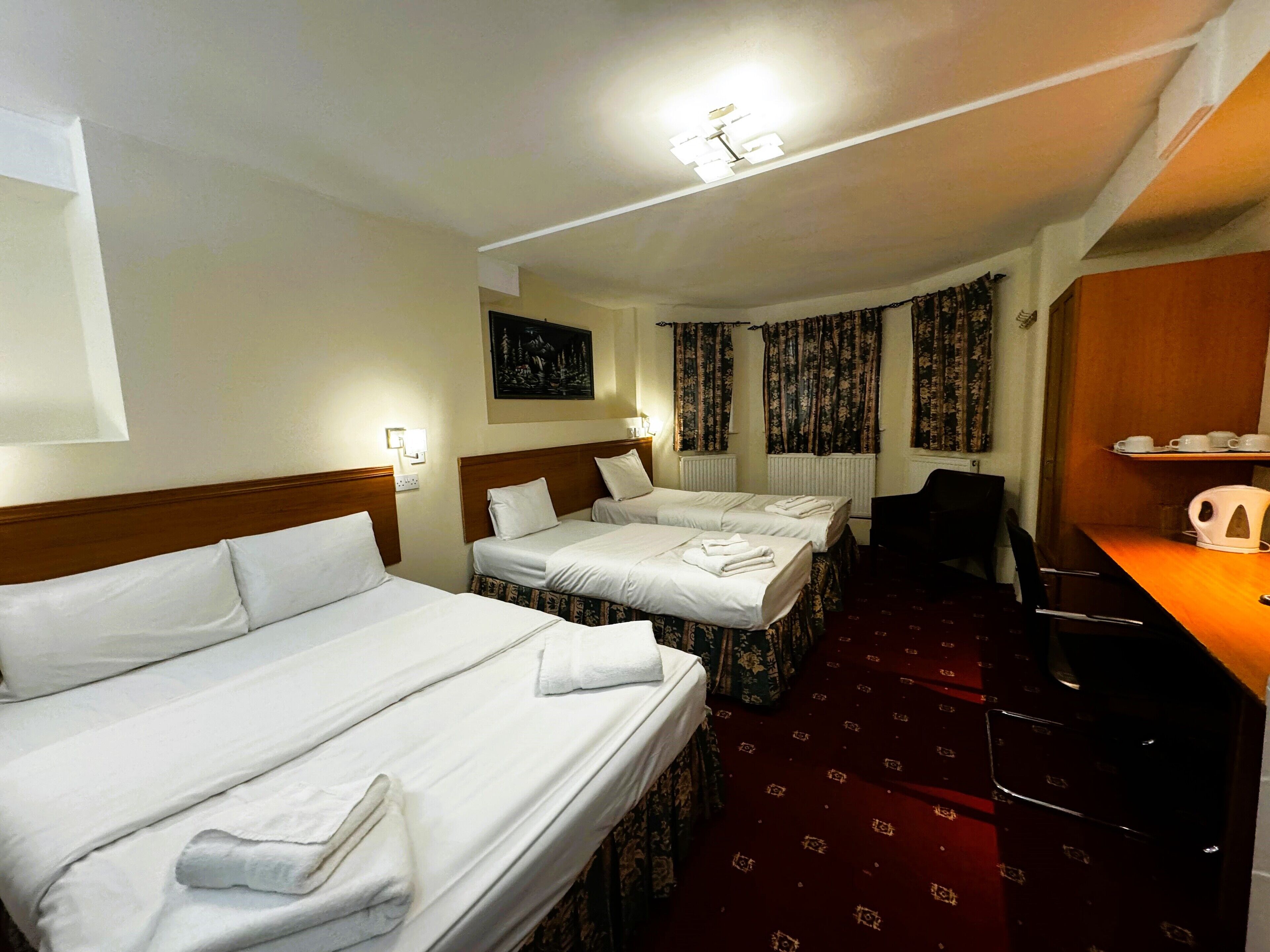 A hotel room with two beds, a desk, a chair, and a coffee maker.