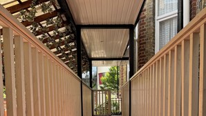 A wooden deck with a sloped ceiling and a view of a brick building in the background. - Bridge Park Hotel (London)