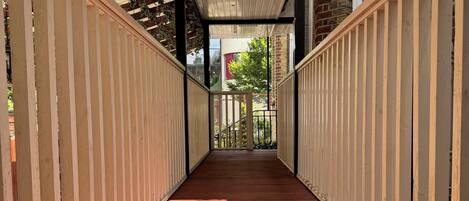 A wooden deck with a sloped ceiling and a view of a brick building in the background.