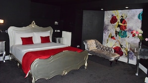 A bedroom with a large bed, a chair, and a wall with a floral painting. - Bridge Park Hotel (London)