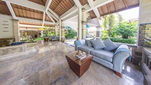 Um hall espaçoso com teto alto, um sofá confortável, uma mesa de centro e vista para o jardim.