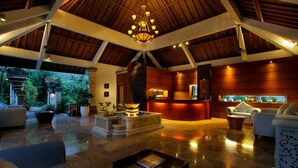 Um lobby amplo com teto alto, uma fonte central e um balcão de recepção.