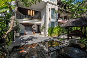 A modern building with a central staircase, a koi pond, and lush greenery.