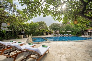 A pool area with lounge chairs, a swimming pool, and surrounding greenery.
