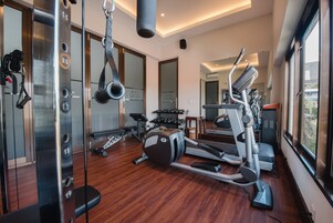 A gym with exercise equipment, a mirror, and a wooden floor.
