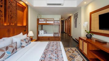 Une chambre d’hôtel avec un grand lit, un lit superposé, une télévision et une armoire en bois.
