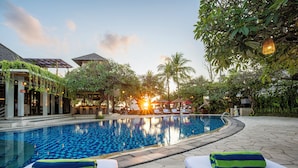 A swimming pool with lounge chairs and a sunset in the background. - Kuta Seaview Beach Resort    (Kuta)